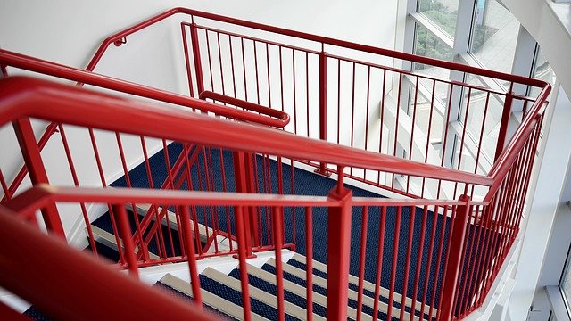 Photo of a stairwell in a building, with a red banister